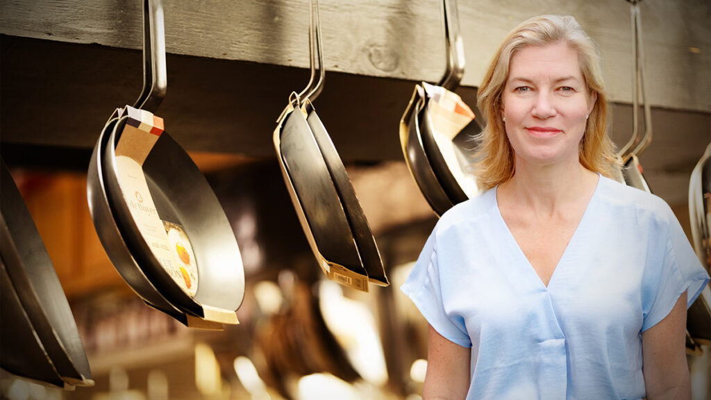 Anne-Sofie Bäckar in front of hanging frying pans